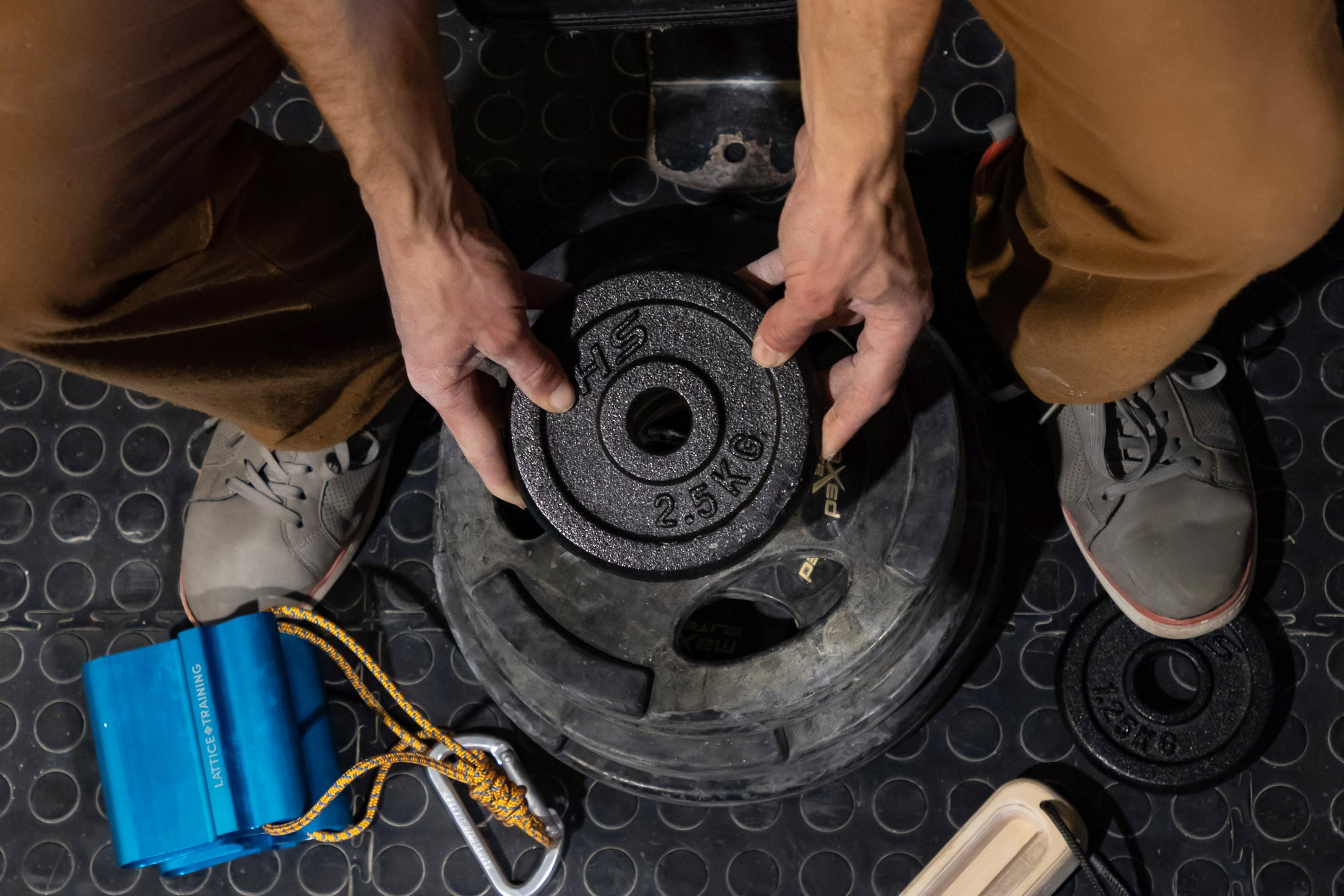 Climber loading weight plates onto lifting pin