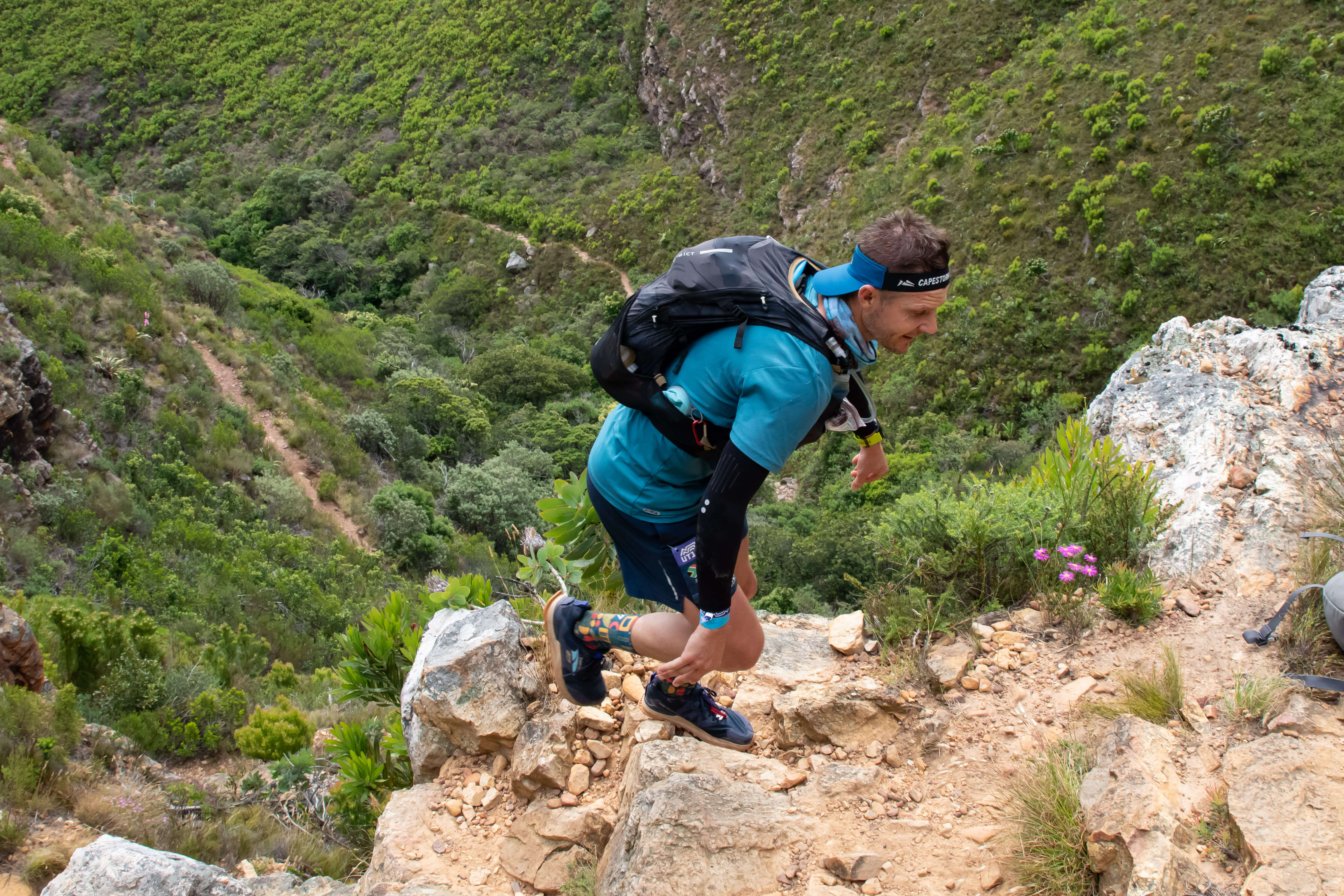 man running trail with mountains in background