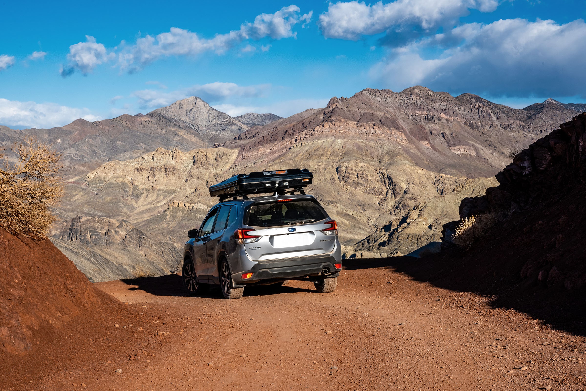 SUV with rooftop tent driving dirt road