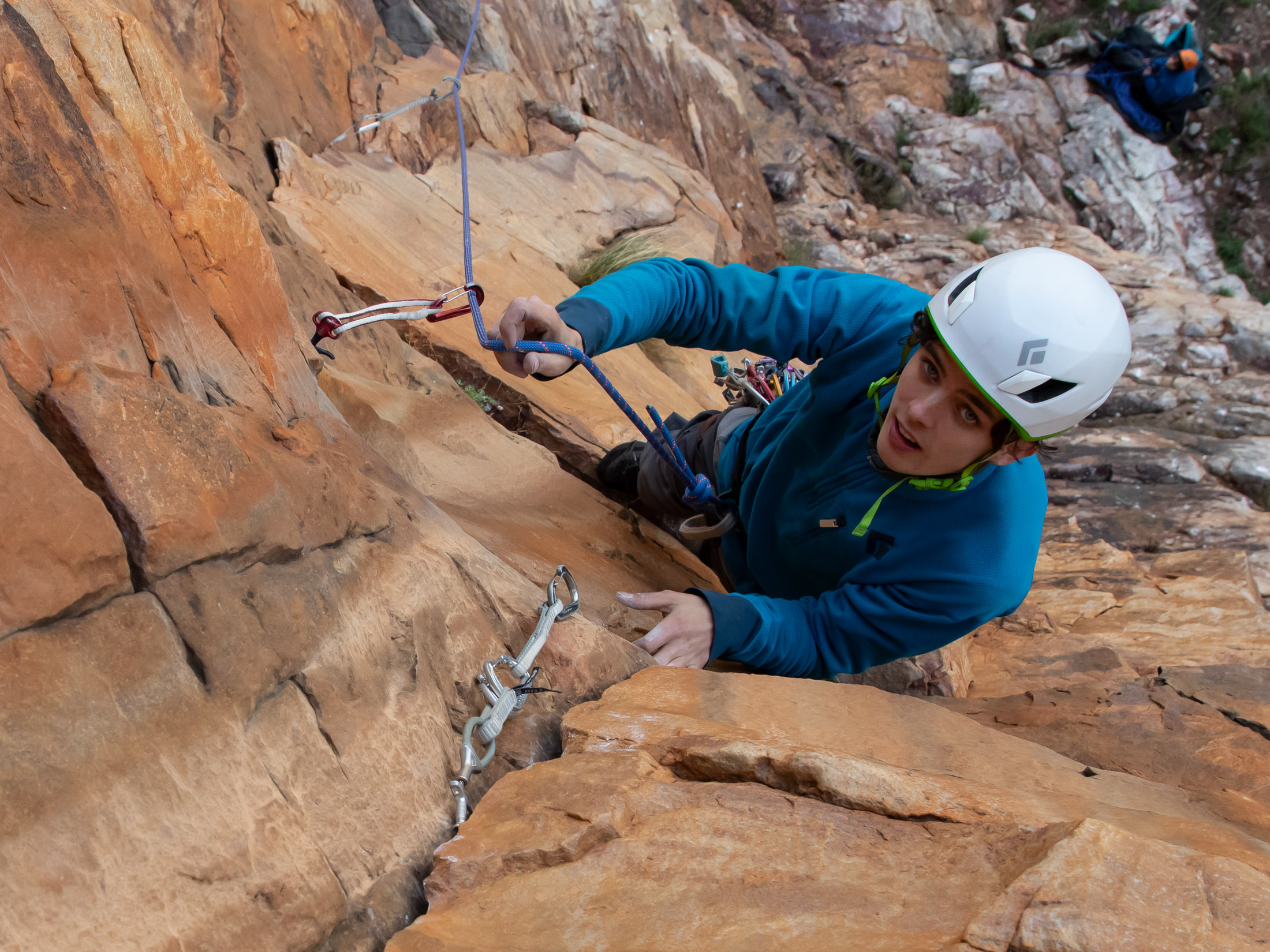 Climber clipping trad gear on route