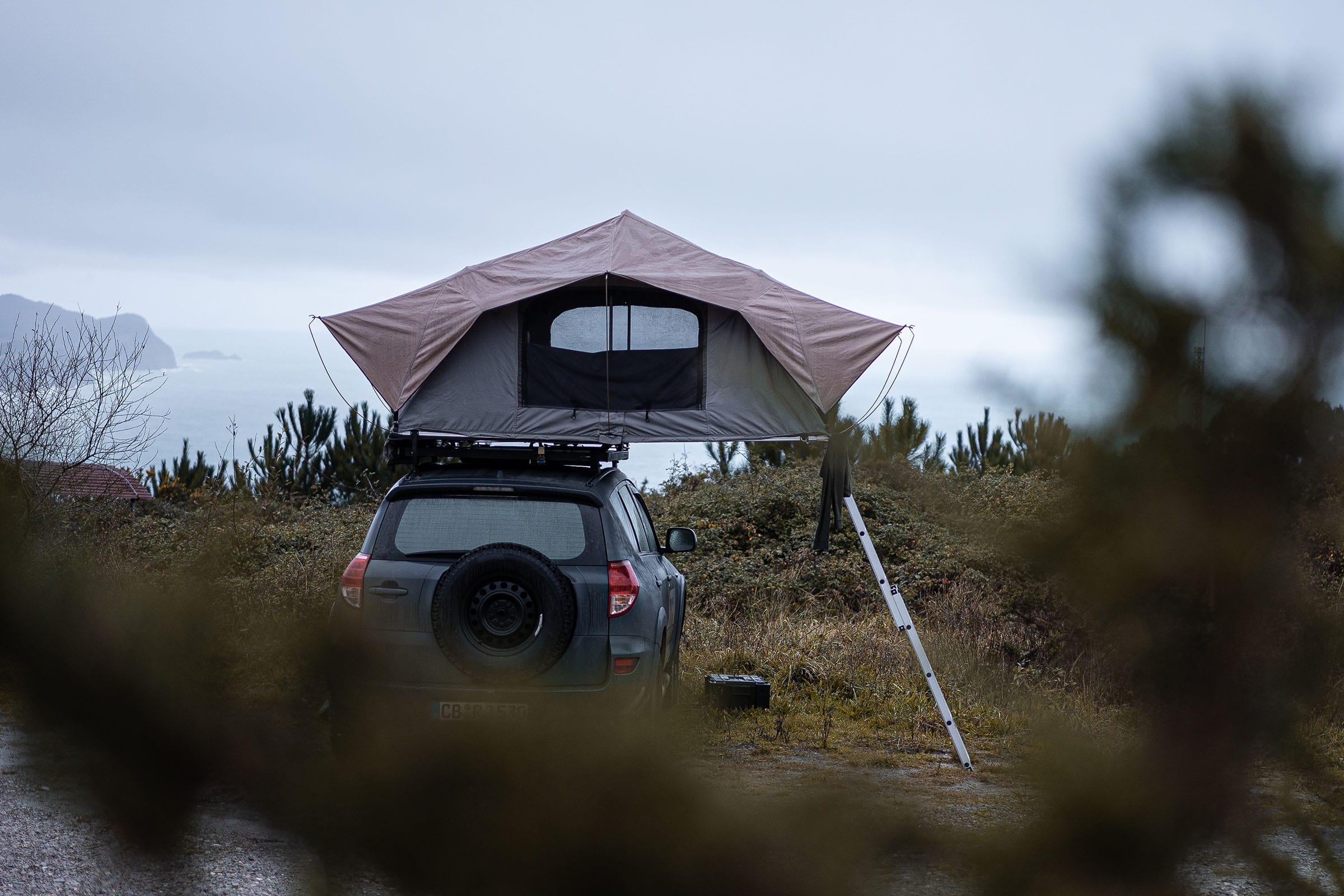 SUV with rooftop tent parked at spot with view of sea