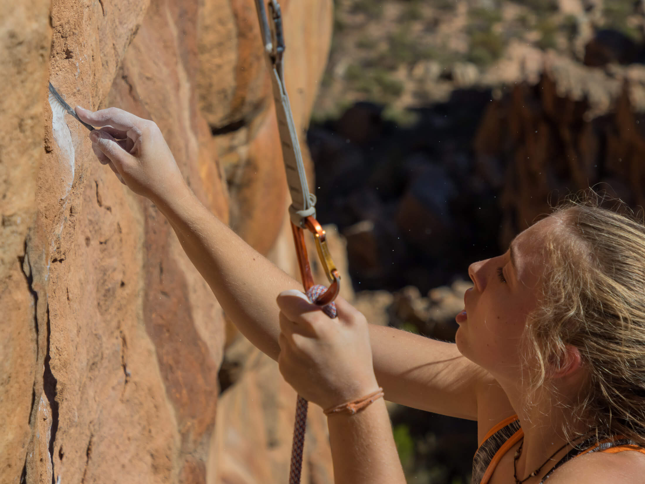 a climber brushes the chalk off holds on a route
