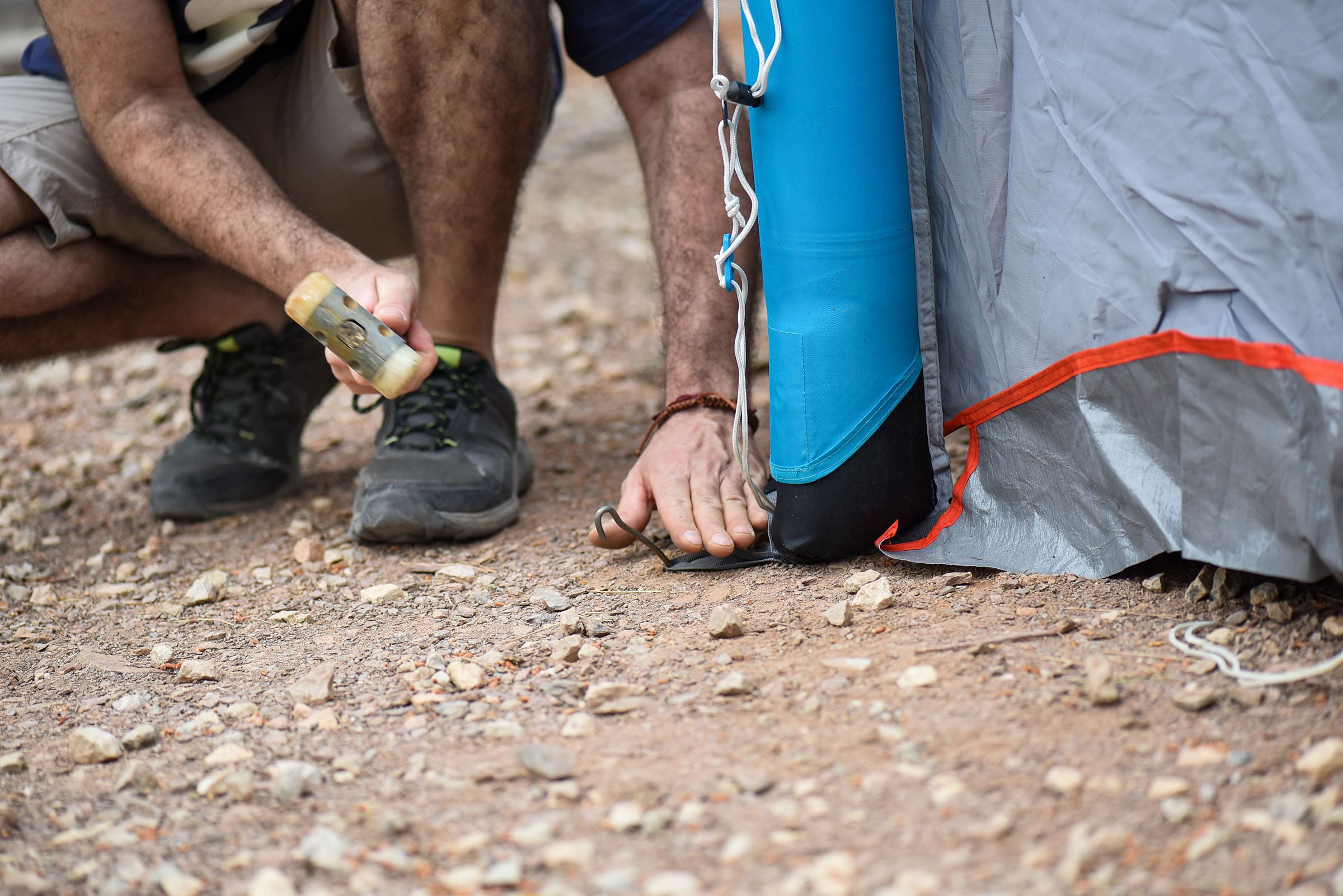 camper securing a tent guy line with a stake