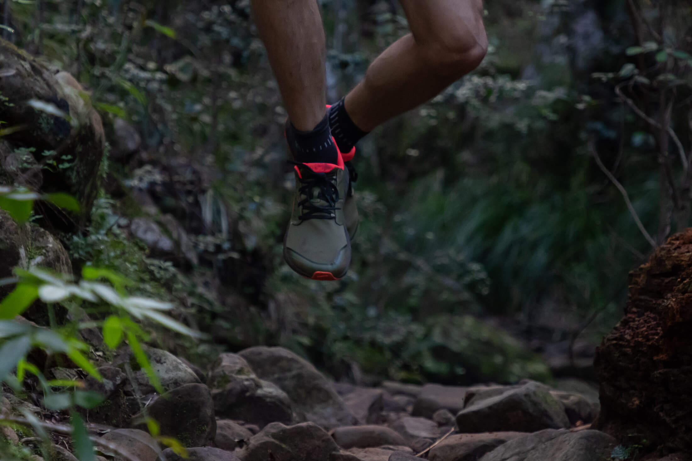 runner jumping over tech section of trail