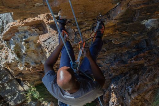 climber cleaning quickdraws off a steep route